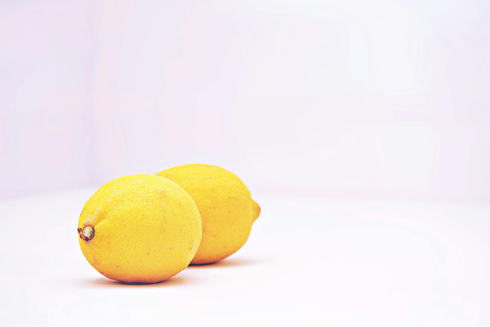 Two vibrant lemons against a white background, symbolizing freshness and renewed sensation
