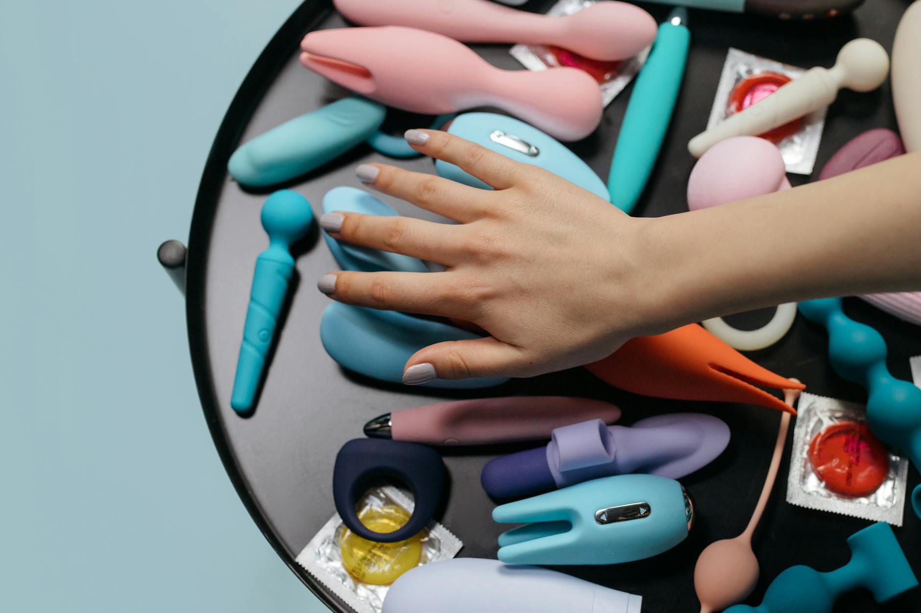 A hand holding a modern orange vibrator against a purple backdrop, representing intimate self-care.