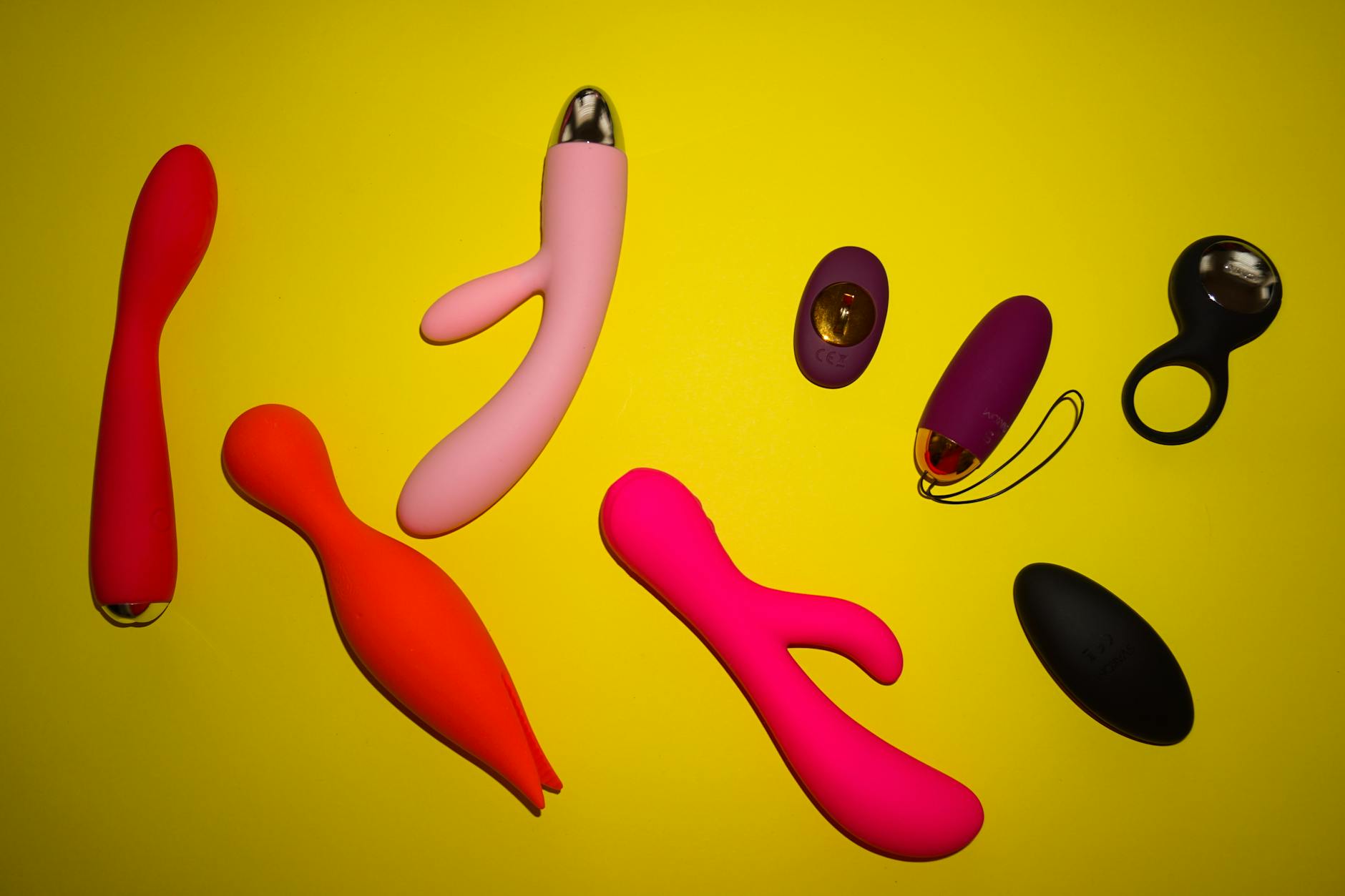 Woman holding colorful vibrators against purple background