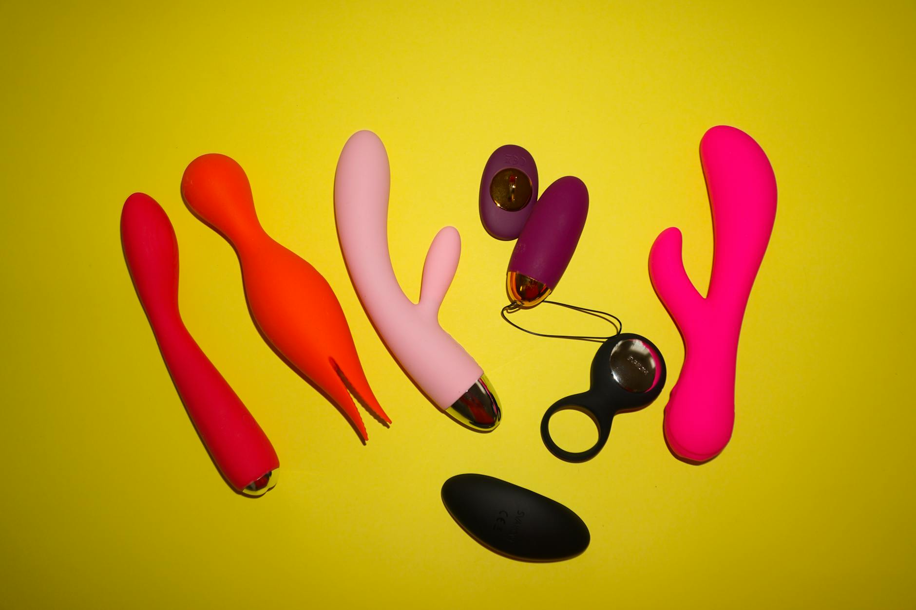 Colorful personal vibrators arranged on a bright yellow background